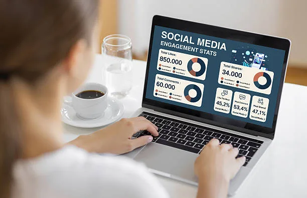 A woman working on a laptop displaying social media engagement statistics with charts and graphs, symbolizing marketing, communication, and online performance.